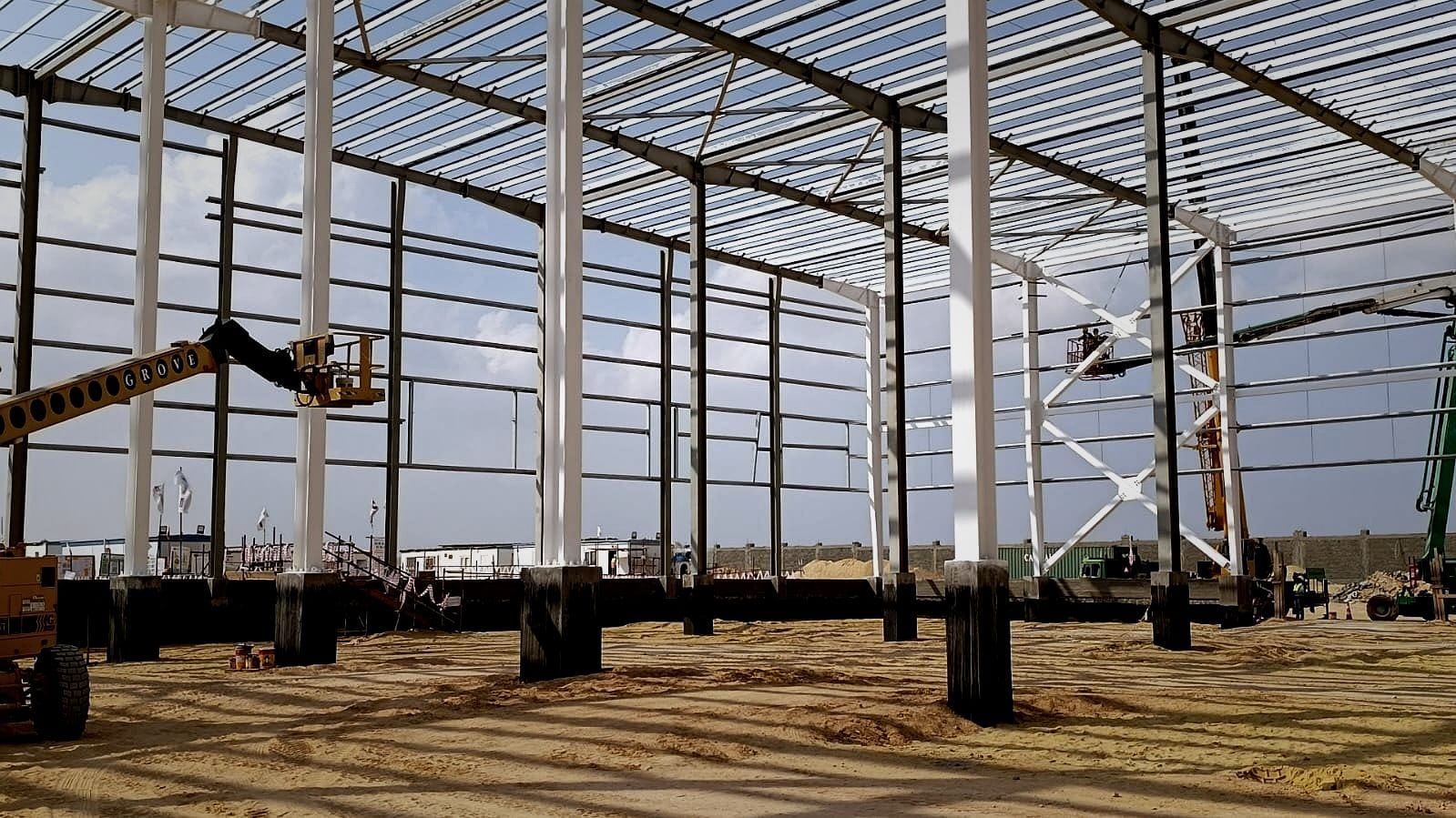 Painted steel columns and roof purlins during erection, with a boom lift at work
