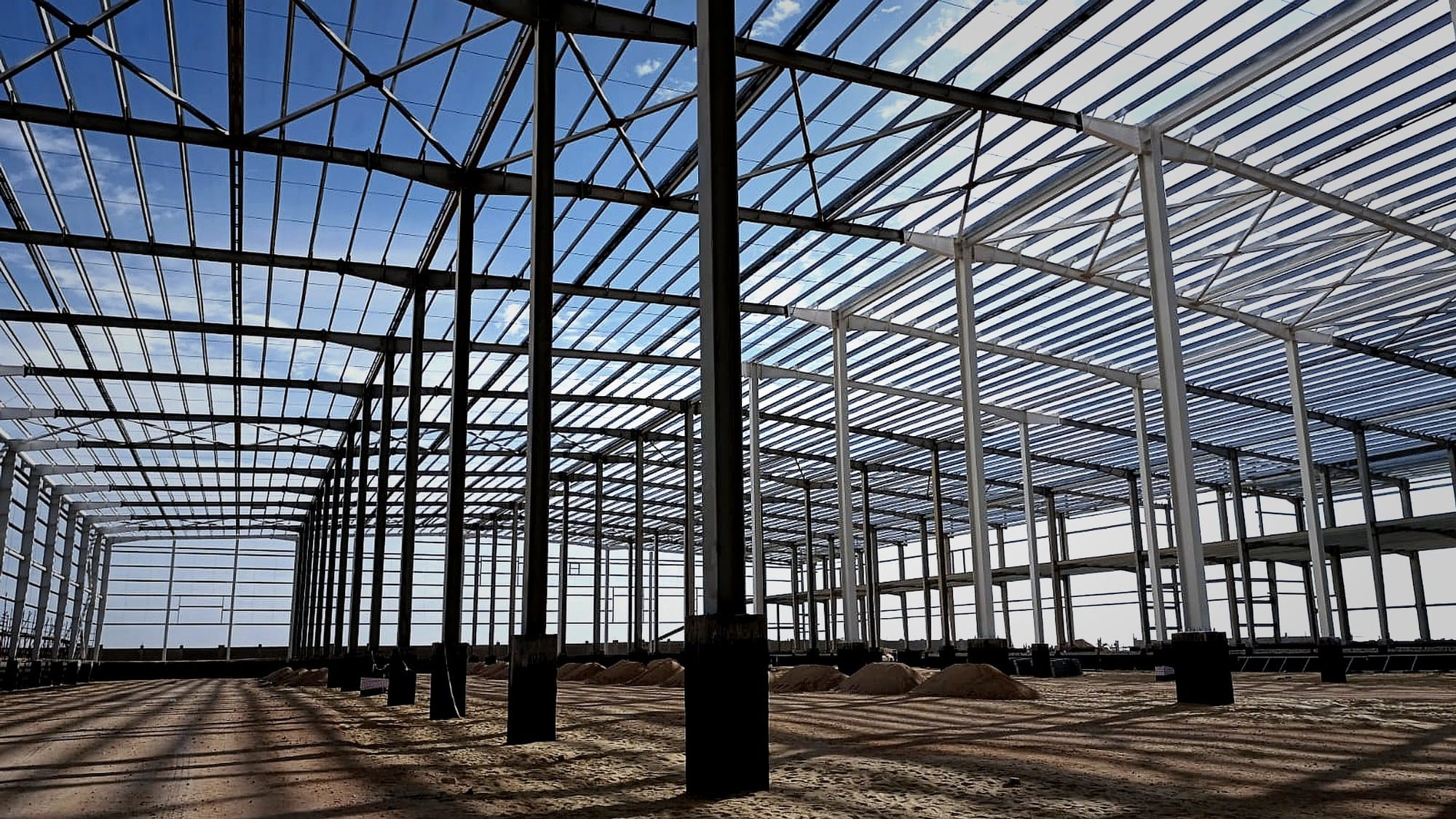 Inside the medical warehouse steel frame, columns, rafters and roof purlins against a blue sky